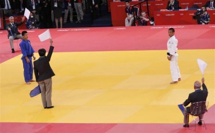 Các trọng tài giương cờ trắng để công bố chiến thắng cho Masashi Ebinuma (trắng) là người chiến thắng mới trong trận tứ kết nội dung judo nam hạng 66kg trước Cho Jun-ho (xanh) của Hàn Quốc.